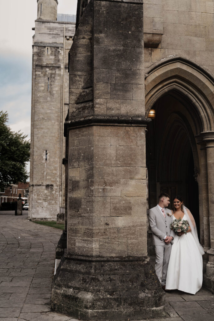 Bride and groom sharing a moment outside the Romsey Abbey, captured by a documentary style photographer.