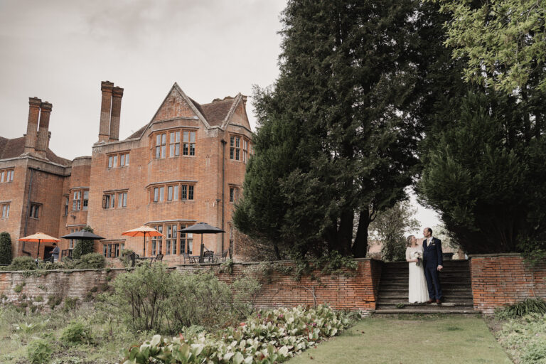 A intimate photo of a newlywed couple sharing gazing into each others eyes against the backdrop of a Hampshire manor house, captured by a documentary-style wedding photographer.